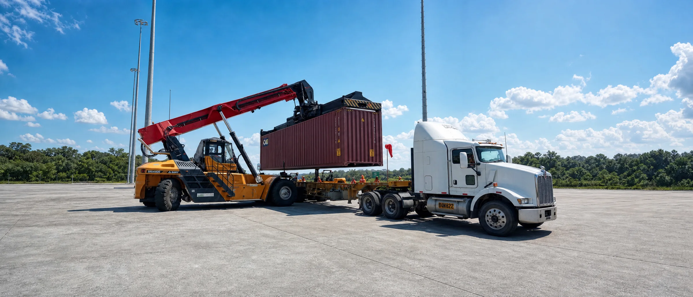 Reach stacker cargando un contenedor sobre un camión en el patio del terminal